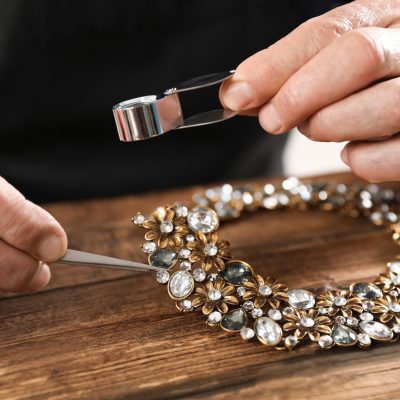 Male jeweler evaluating necklace at table in workshop, closeup